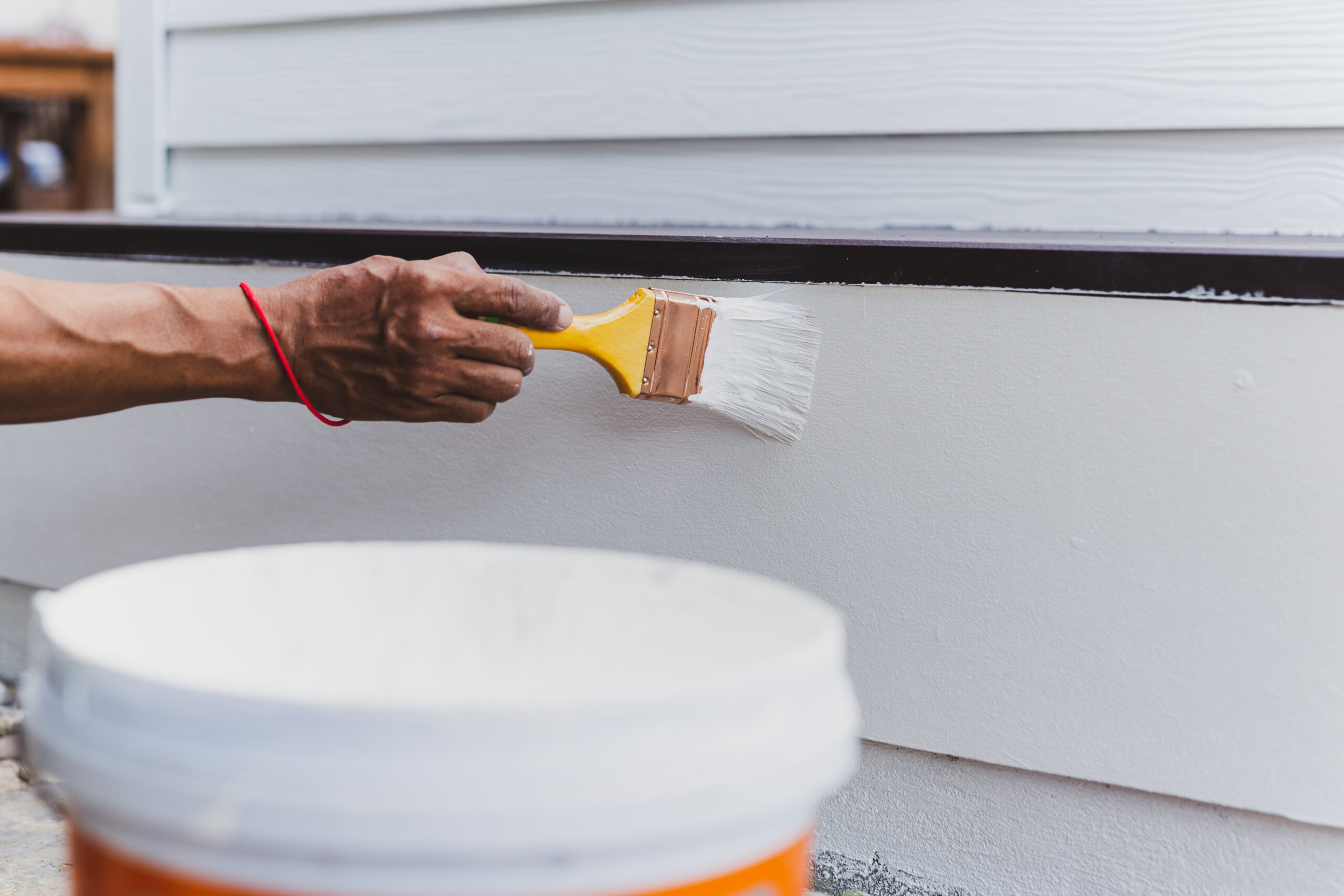 Hand painting outside wall with white color.